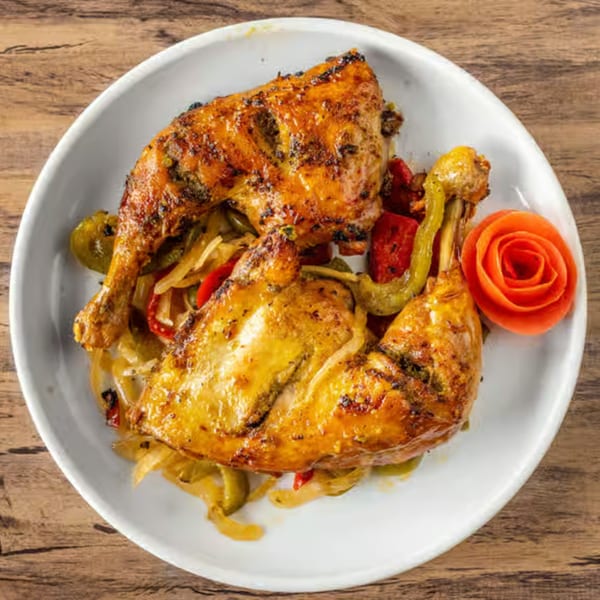 Two pieces of grilled chicken with sautéed onions and peppers, garnished with a tomato rose.