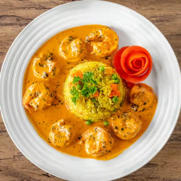 Choukouya Resto-Bar's African shrimp dish with yellow rice, vegetables, and a tomato garnish.