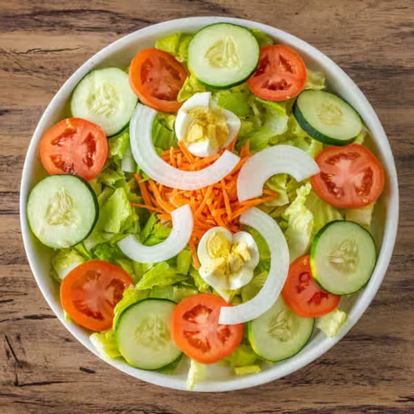 Fresh garden salad with lettuce, tomatoes, cucumbers, onions, shredded carrots, and hard-boiled eggs.