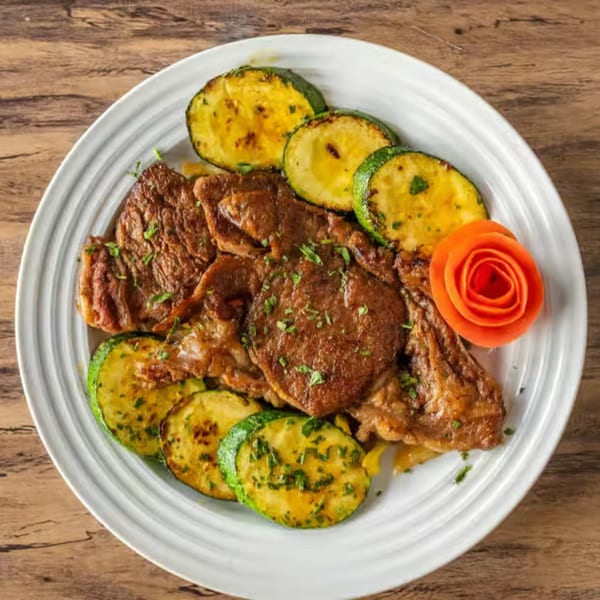 Choukouya Resto-Bar's African grilled meat with zucchini and a carrot garnish on a white plate.
